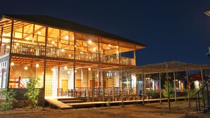A two-story building with a covered outdoor seating area and a balcony.