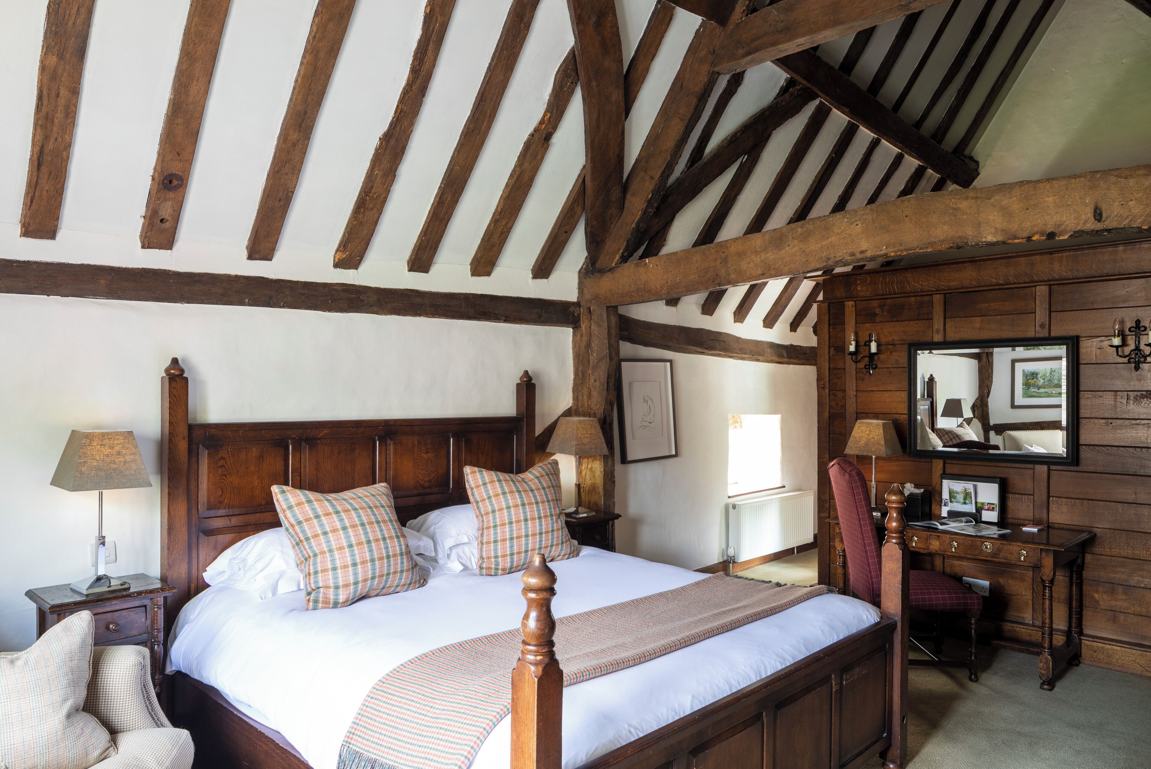 A bedroom with a wooden bed, a desk, and a chair.