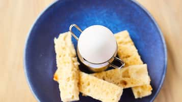 A blue plate with a white cup and several pieces of bread.