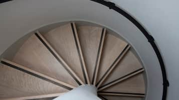 Una escalera de caracol con escalones de madera y detalles en negro, que asciende en forma circular.