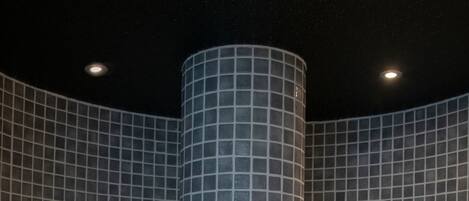 A circular hot tub with a grid-patterned wall surrounding it.