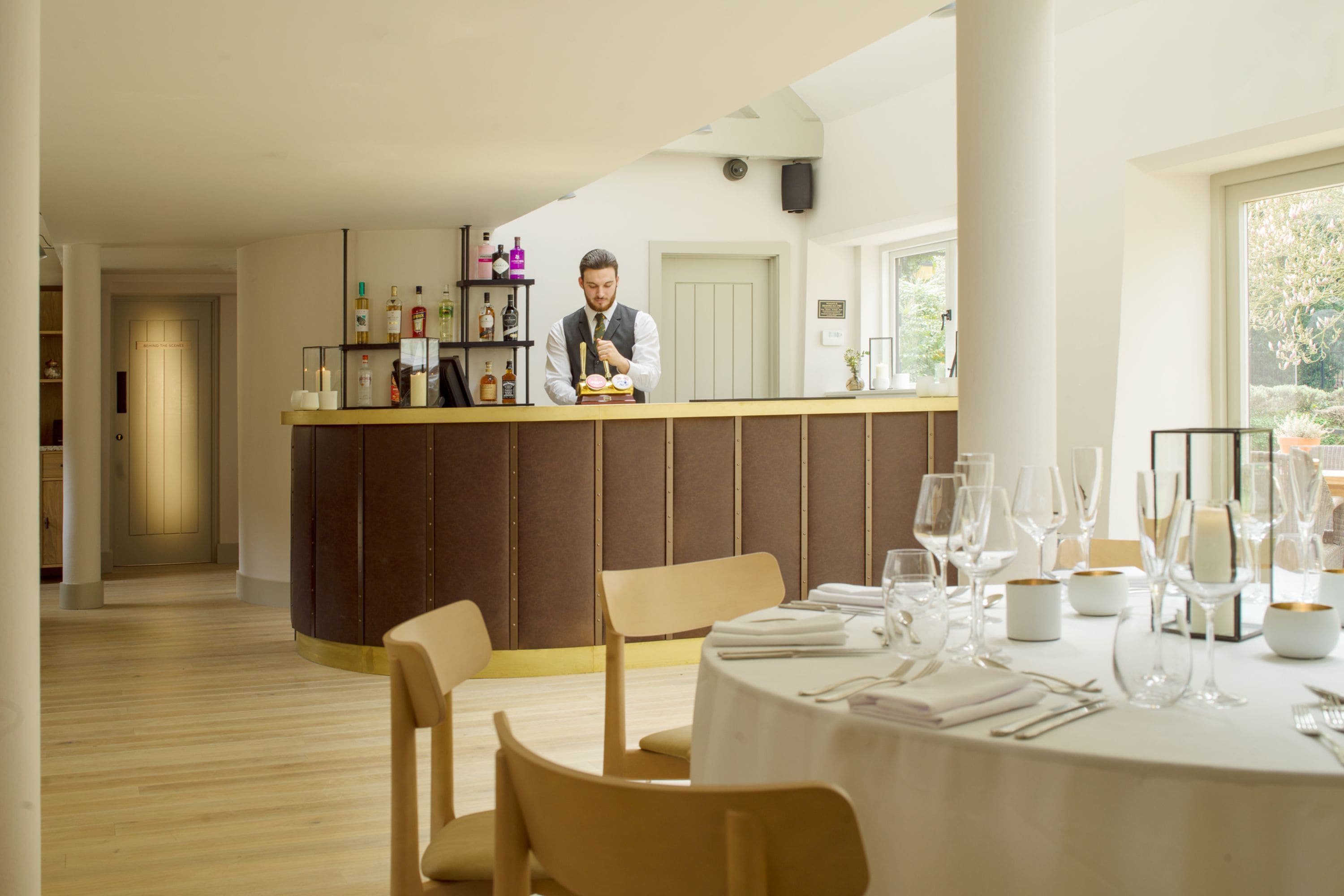 Un restaurant doté d’un bar, d’un sol en bois et d’une table dressée pour le dîner.