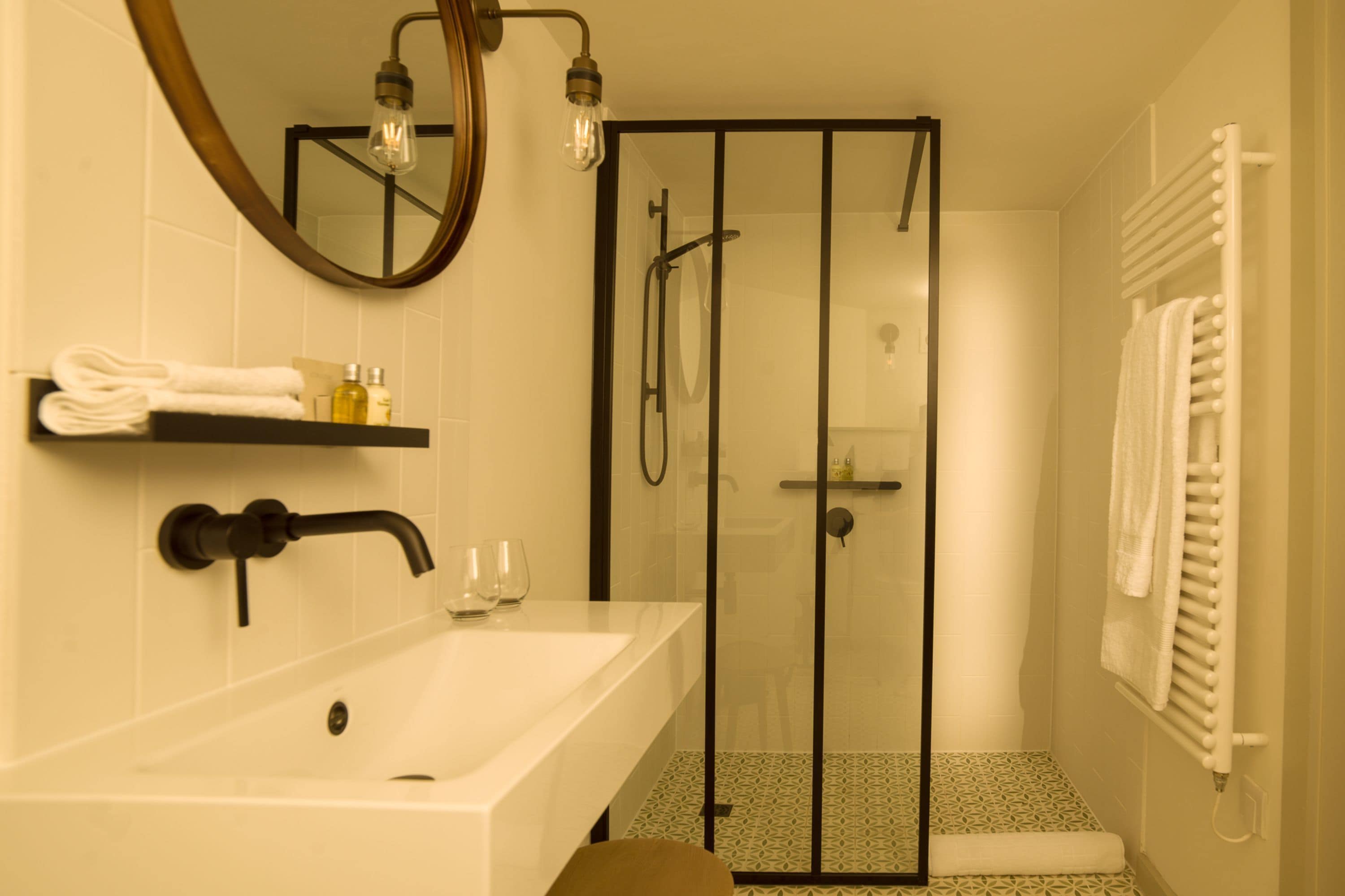 Un baño con lavamanos blanco, cabina de ducha de vidrio y un perchero para toallas.