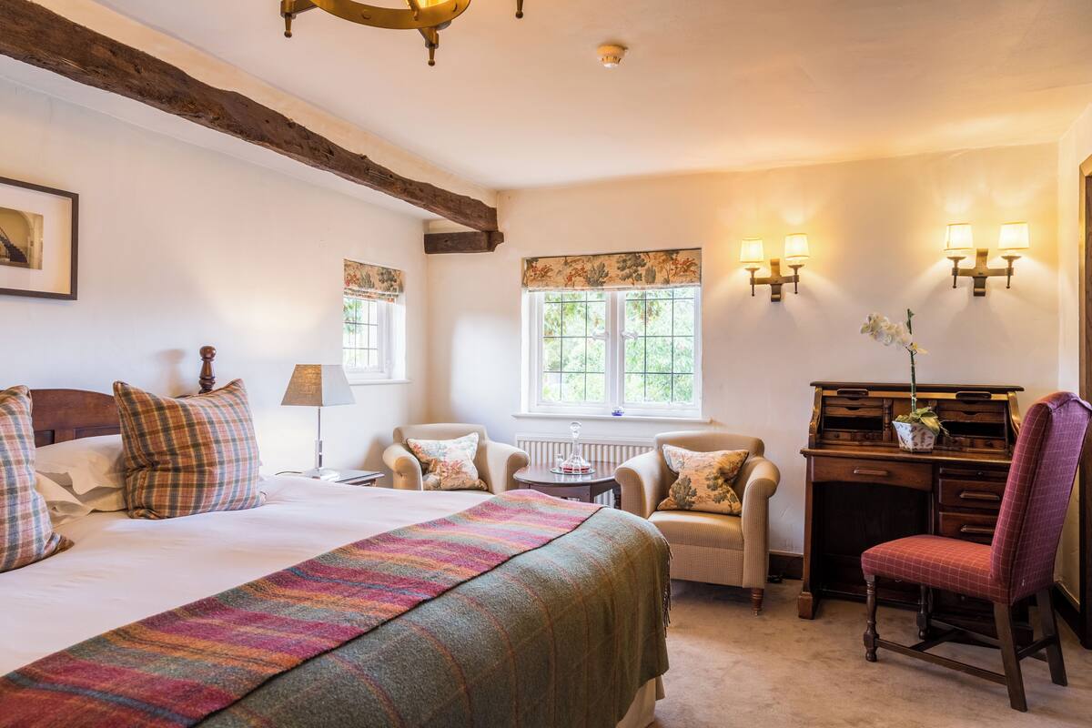 Une chambre confortable avec un lit, un bureau et deux chaises.
