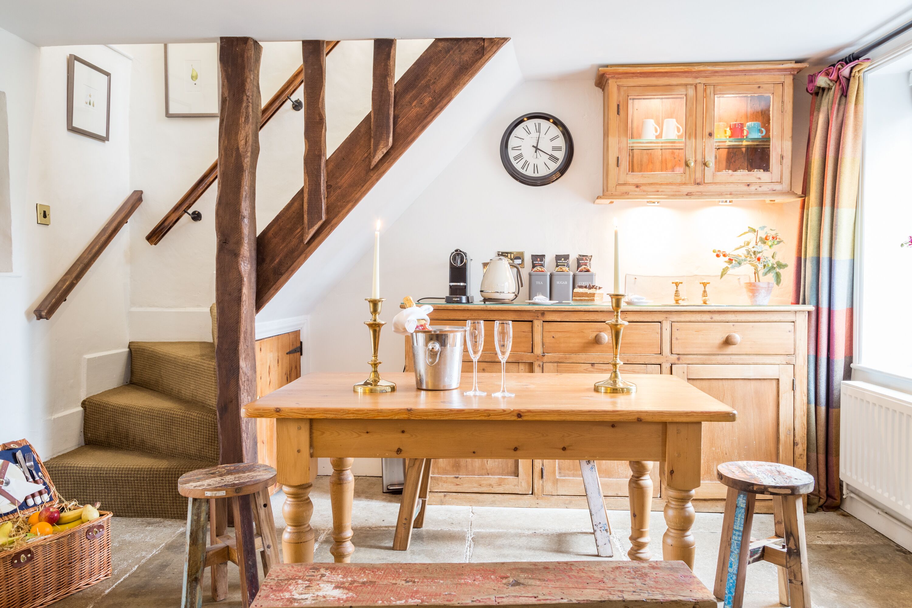 A cozy kitchen with wooden cabinets, a dining table, and a staircase.