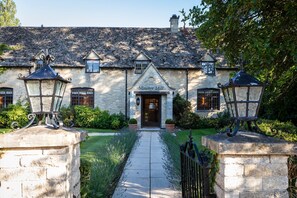 A stone building with a sign reading "Minster Mill," featuring a traditional design with a tiled roof, a central entrance, and two lantern-style lights on either side. - Old Swan & Minster Mill Hotel (Witney)
