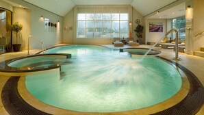 An indoor swimming pool with a circular design, seating areas, and large windows providing natural light. - Old Swan & Minster Mill Hotel (Witney)
