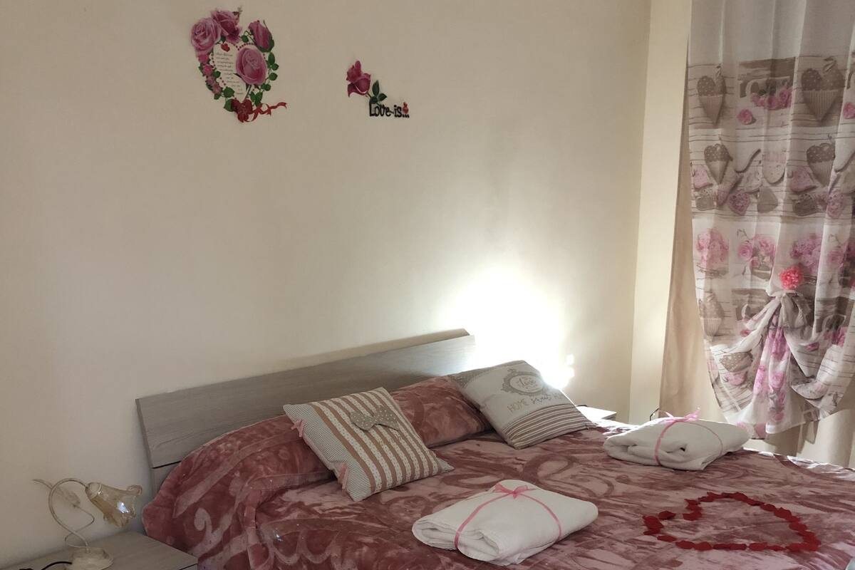 A bedroom with a bed, pillows, a nightstand, and a lamp.