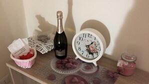 Een houten bureau met een klok, champagnefles, een mand en een pot.