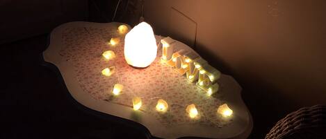 A table with a floral tablecloth, a glowing light in the center, and string lights around it.