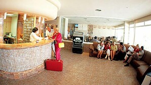 A lobby with a reception desk, a coffee machine, and a seating area with people. - Apartamentos Esmeralda (Calpe)
