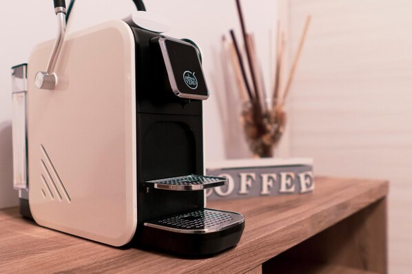 A coffee machine on a wooden surface with a "COFFEE" sign in the background. - Il Vicolo B&B (Putignano)