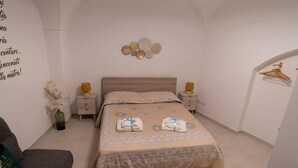 A neatly arranged bedroom with a bed, bedside tables, a dresser, and a wall with decorative plates. - Il Vicolo B&B (Putignano)