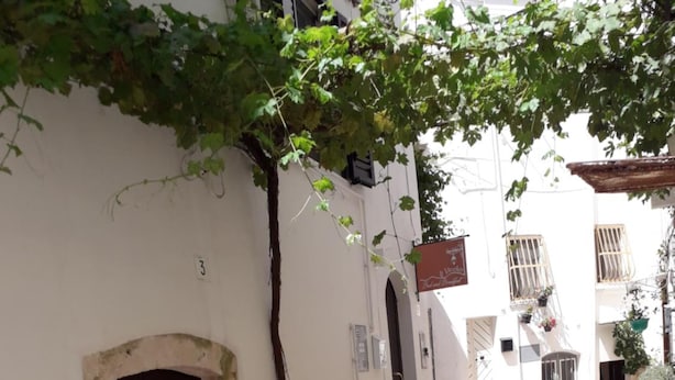 A narrow stone-paved alleyway with a dark door and a small tree. - Il Vicolo B&B (Putignano)