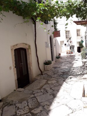 A narrow stone-paved alleyway with a dark door and a small tree. - Il Vicolo B&B (Putignano)