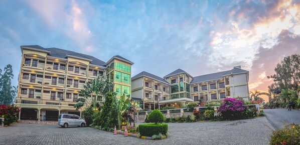 Un hotel de varios pisos con un patio central, rodeado de exuberante vegetación y plantas decorativas.