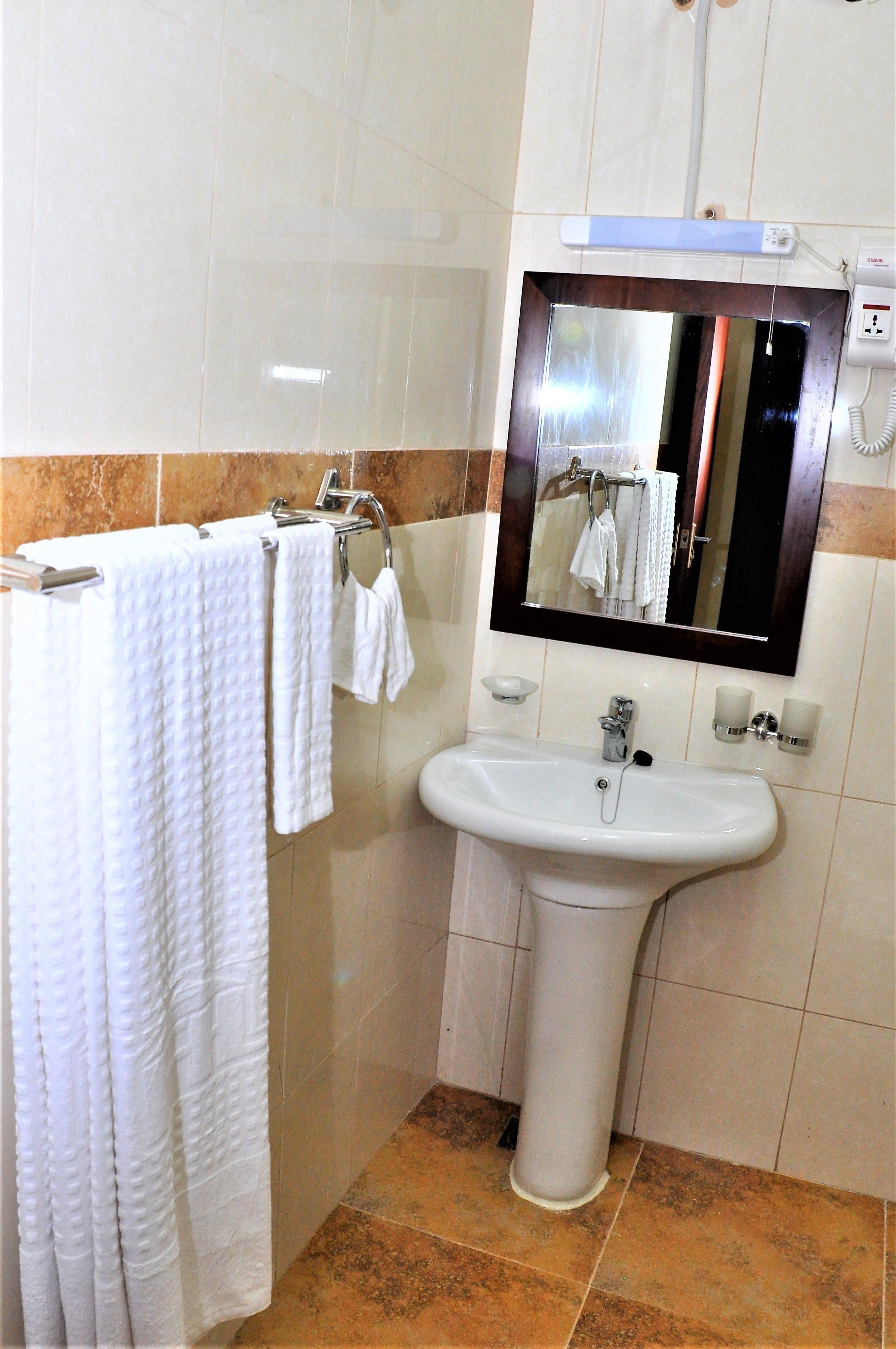 Un baño con lavamanos, espejo y toallero.