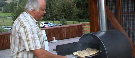 A man cooking pizza on an outdoor grill.