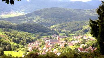 A rural village with a church and residential buildings surrounded by green hills.