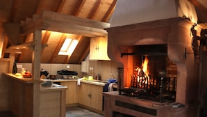 Une cuisine rustique avec une cheminée en pierre, des poutres en bois et une lucarne.