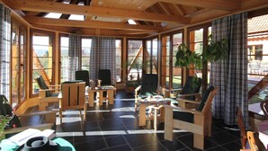 Un intérieur en bois, doté de grandes fenêtres, d’un coin repas et d’un espace salon.