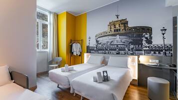 Ein Hotelzimmer mit zwei Betten, einem großen Wandgemälde eines historischen Gebäudes, einem Schreibtisch mit Lampe und einem Sessel.