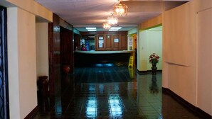 A hotel lobby with a reception desk, a chandelier, and a wet floor sign. - Hotel Maya Excelsior (Guatemala City)