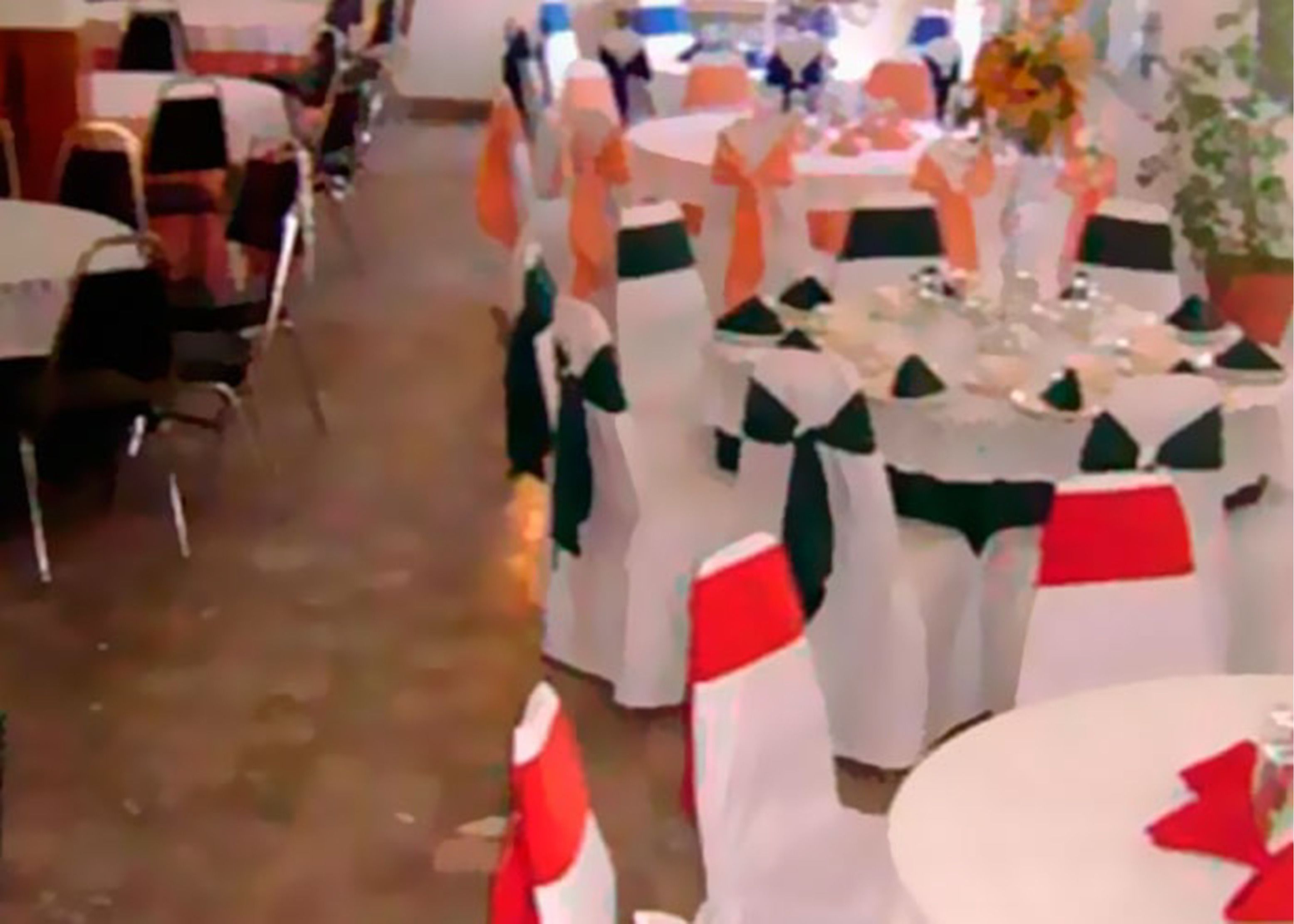 A banquet hall with round tables, each adorned with white tablecloths and green sashes.