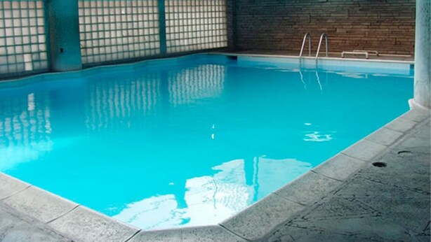 An indoor swimming pool with clear blue water, tiled walls, and a brick accent wall. - Hotel Maya Excelsior (Guatemala City)