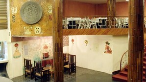 A lobby with a large decorative wall, a staircase, and several wooden chairs. - Hotel Maya Excelsior (Guatemala City)