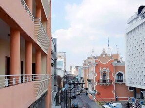 A street view with a building featuring a red facade and white decorative elements. - Hotel Maya Excelsior (Guatemala City)