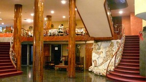A grand lobby with a central staircase, high wooden pillars, and a second-floor balcony. - Hotel Maya Excelsior (Guatemala City)