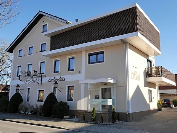 A two-story hotel with a modern design, featuring a prominent entrance with a glass facade, multiple windows, and a balcony on the upper floor.
