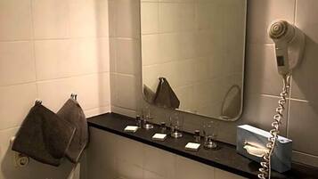A bathroom with a white sink, a mirror, a towel rack, and a hairdryer.