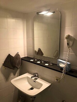 A bathroom with a white sink, a mirror, a towel rack, and a hairdryer.