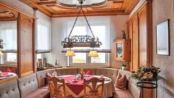 A dining area with a round table, chairs, and a bench. There is a chandelier above the table.