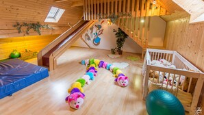 A wooden interior with a sloped ceiling, a staircase, and a crib with stuffed animals. - Gasthof Fischerwirt (Neumarkt in Steiermark)