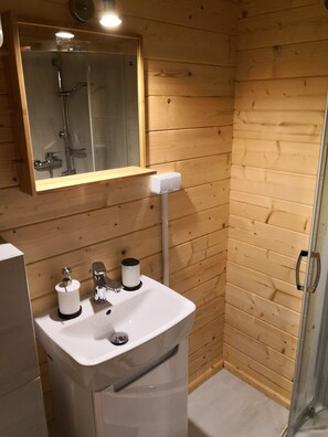 Bathroom features a sink, mirror, glass shower, toilet paper holder, and hand dryer.