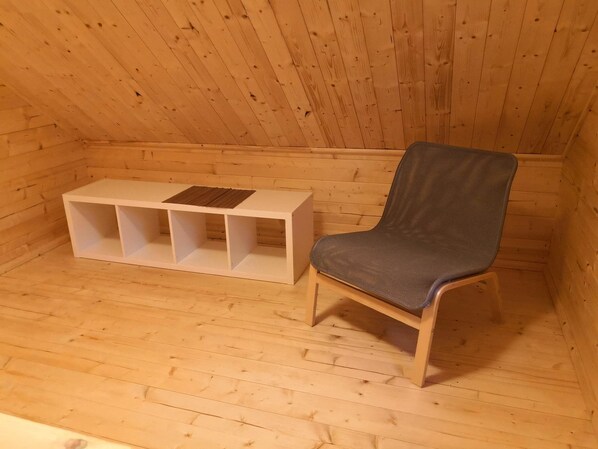 A wooden room with a single chair and a white storage unit.