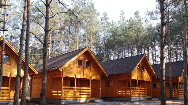 A row of wooden cabins with a simple, rustic design, surrounded by a forest. - Domki Wiosełko (Nasielsk)