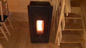 A wood-burning stove in a wooden cabin with a ladder and wooden steps. - Domki Wiosełko (Nasielsk)