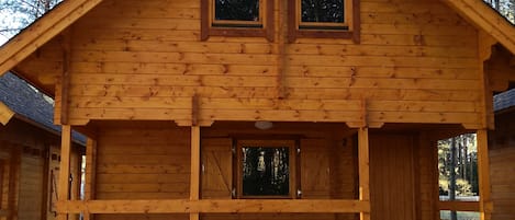 A wooden cabin with a front porch, two windows, and a door.