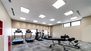 Un gimnasio con cintas de correr, elípticas y equipo de pesas.