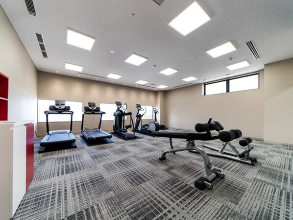 Un gimnasio con cintas de correr, elípticas y equipo de pesas.