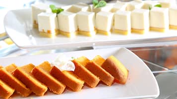 A dessert display with various types of cakes and pastries on white plates.