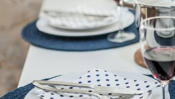 Een eettafel gedekt met borden, bestek en een wijnglas.
