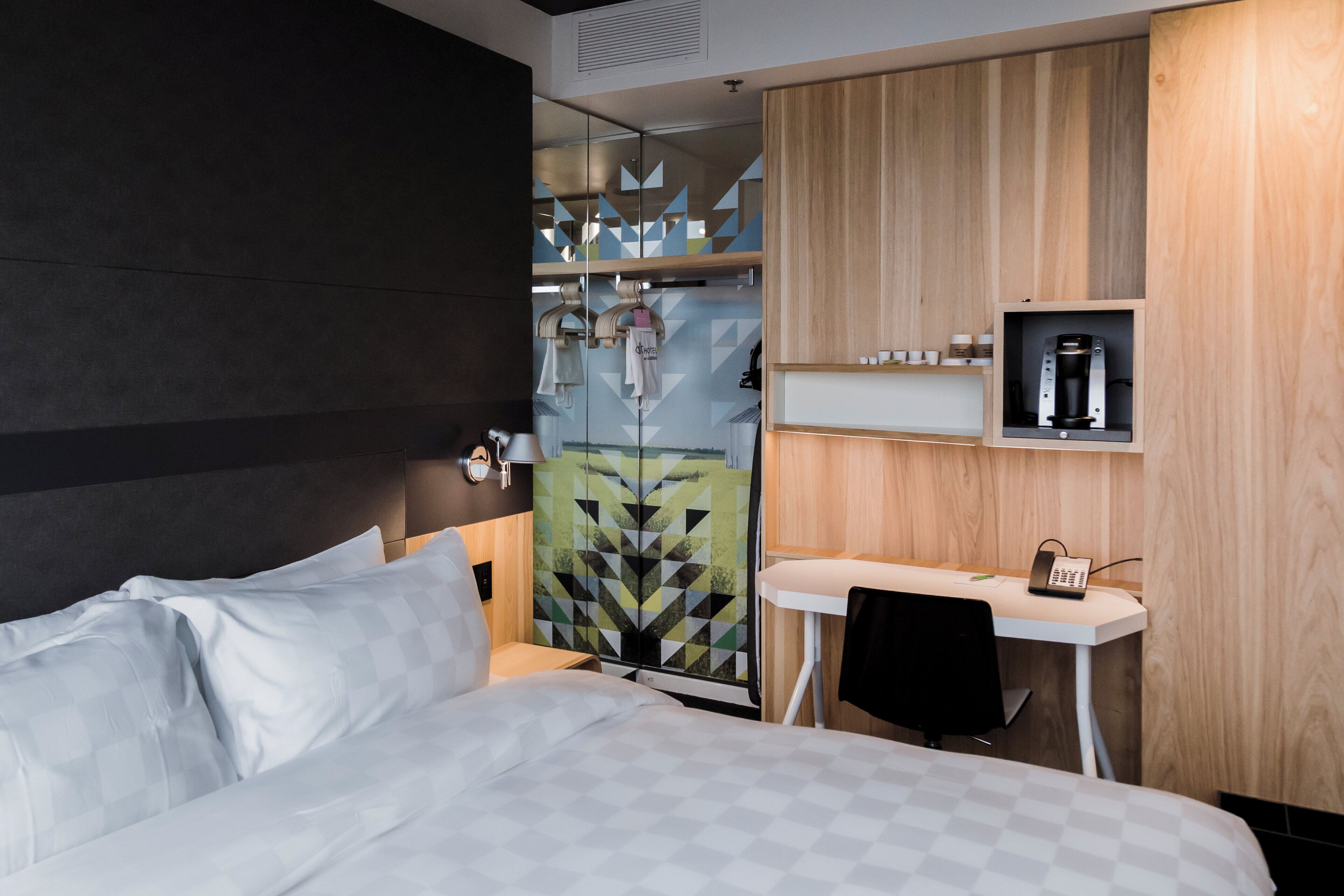 A hotel room with a bed, a desk, and a shower area.