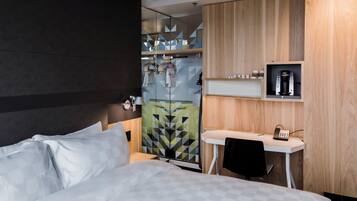 A hotel room with a bed, a desk, and a shower area.