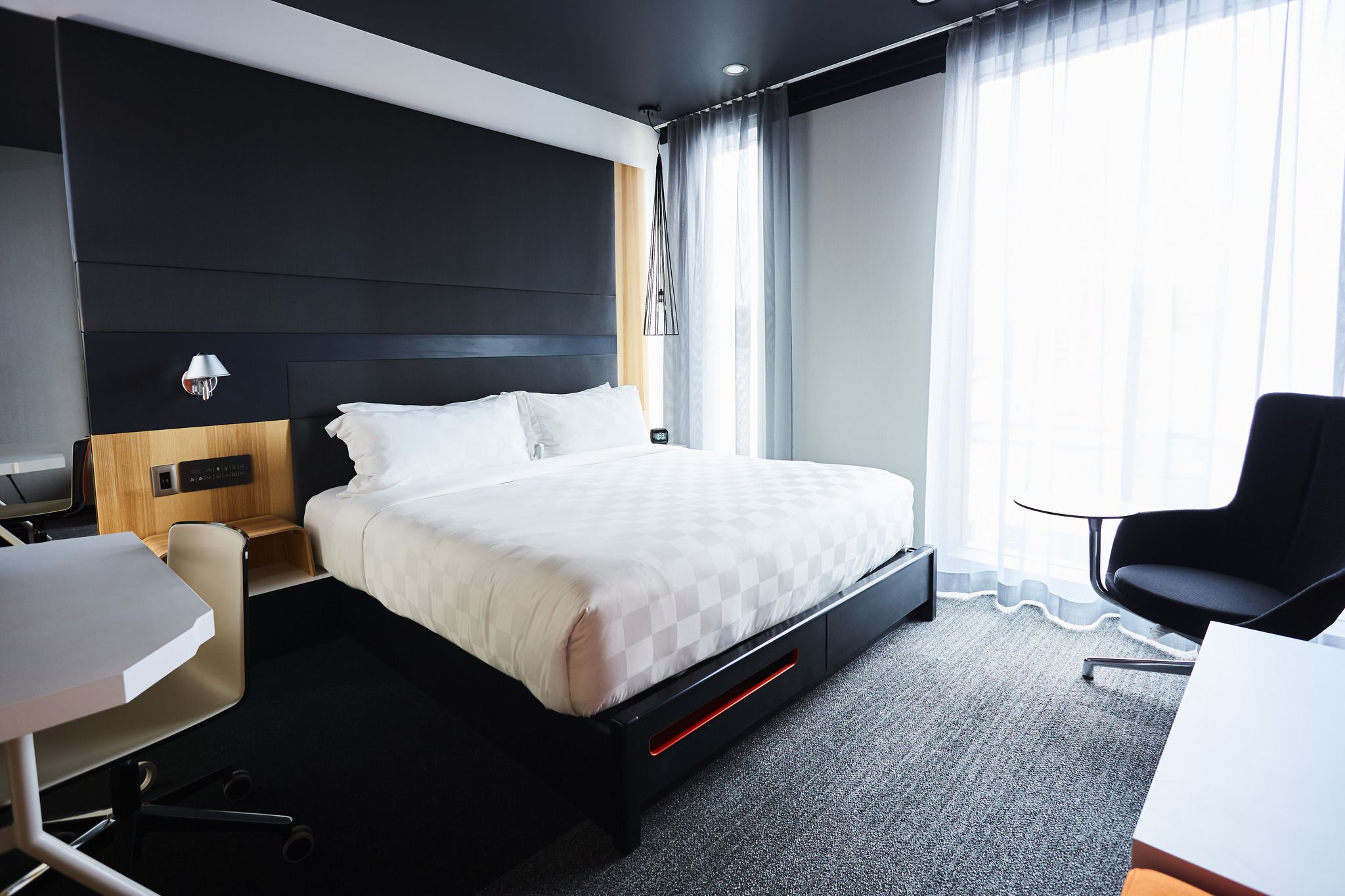 A modern hotel room with a large bed, a desk, and a chair.