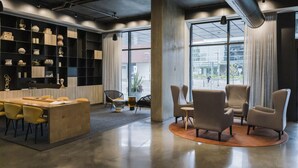 Un vestíbulo moderno de hotel con recepción, zona de estar y exhibición de objetos decorativos.